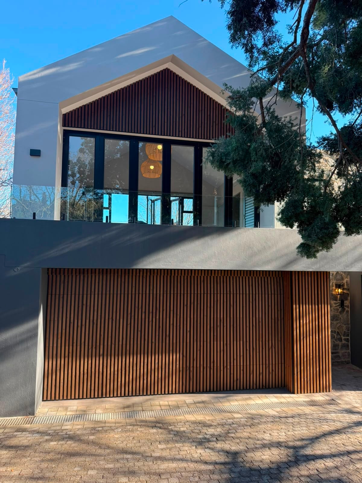 Vertical wood slat exterior cladding covering garage door and upper gable on a house facade