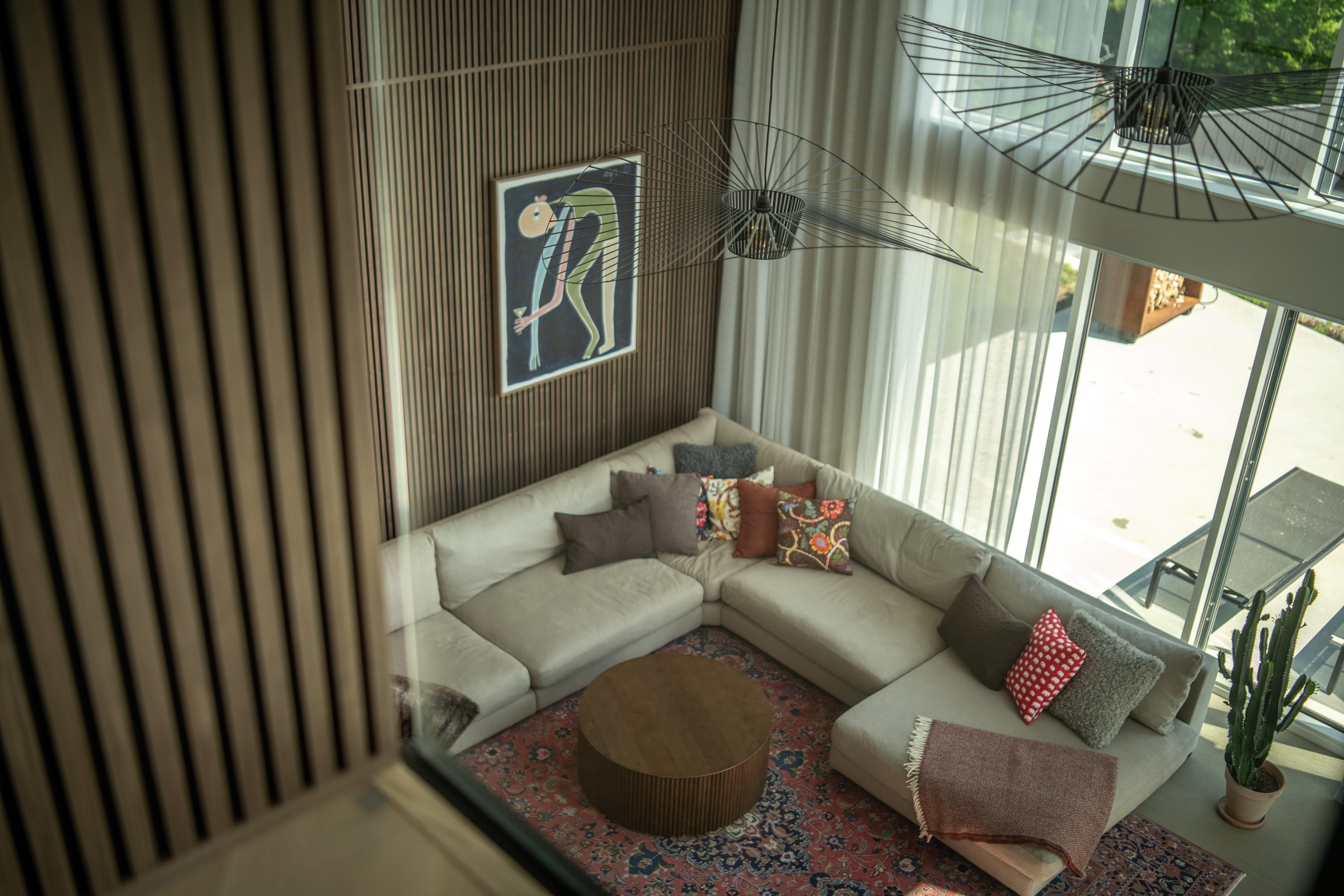 Akupanel acoustic wood slat wall panels on double-height living room wall behind a sectional sofa