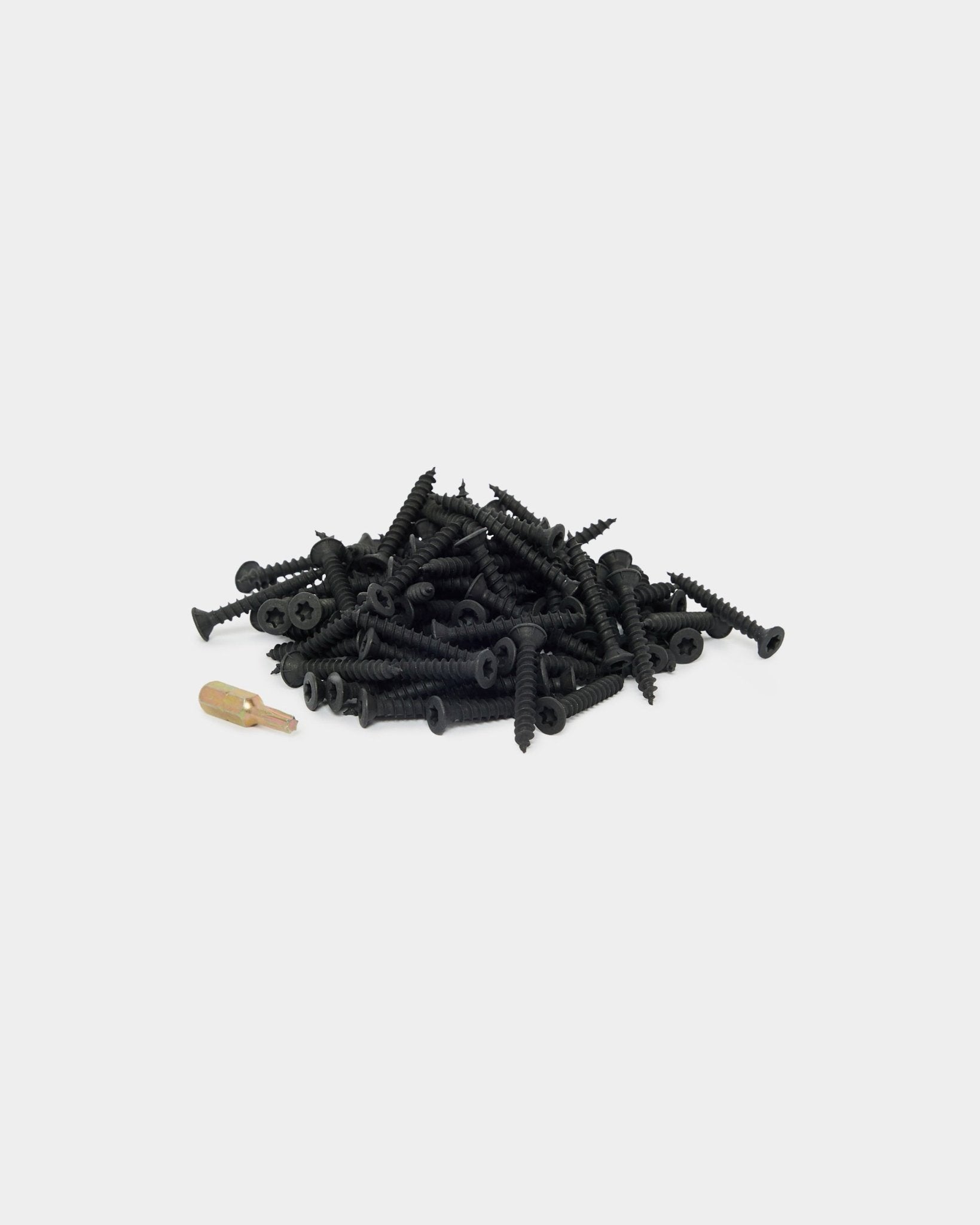 Pile of black mounting screws with a gold driver bit on a plain white background