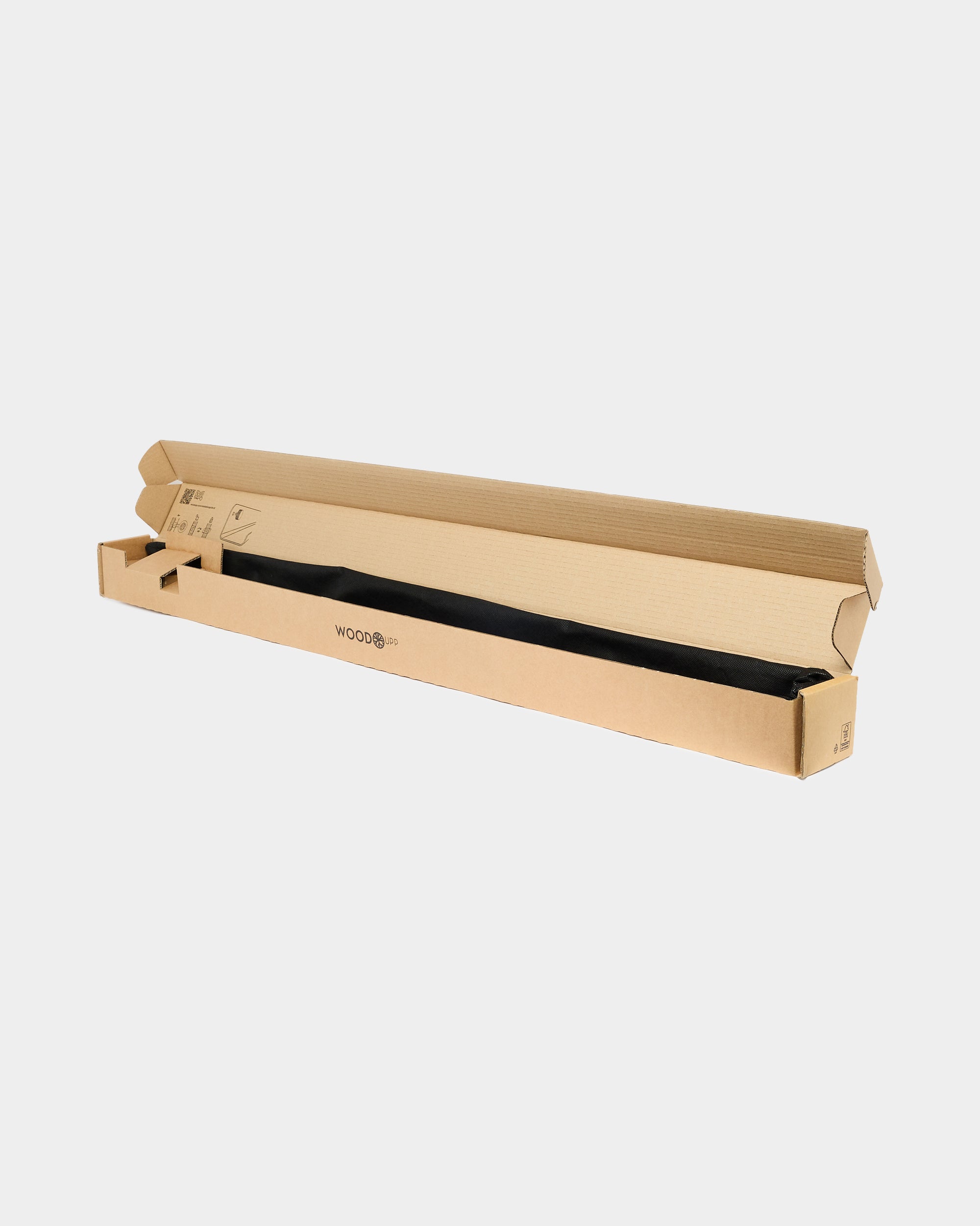 Open long cardboard shipping box with a black fabric-wrapped product on a plain white background