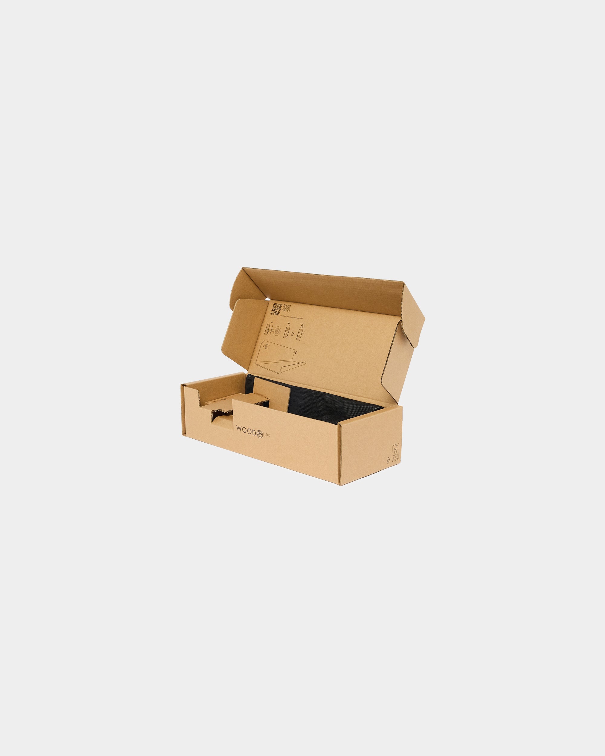 Open brown cardboard box with printed assembly diagrams and black fabric insert on a plain white background