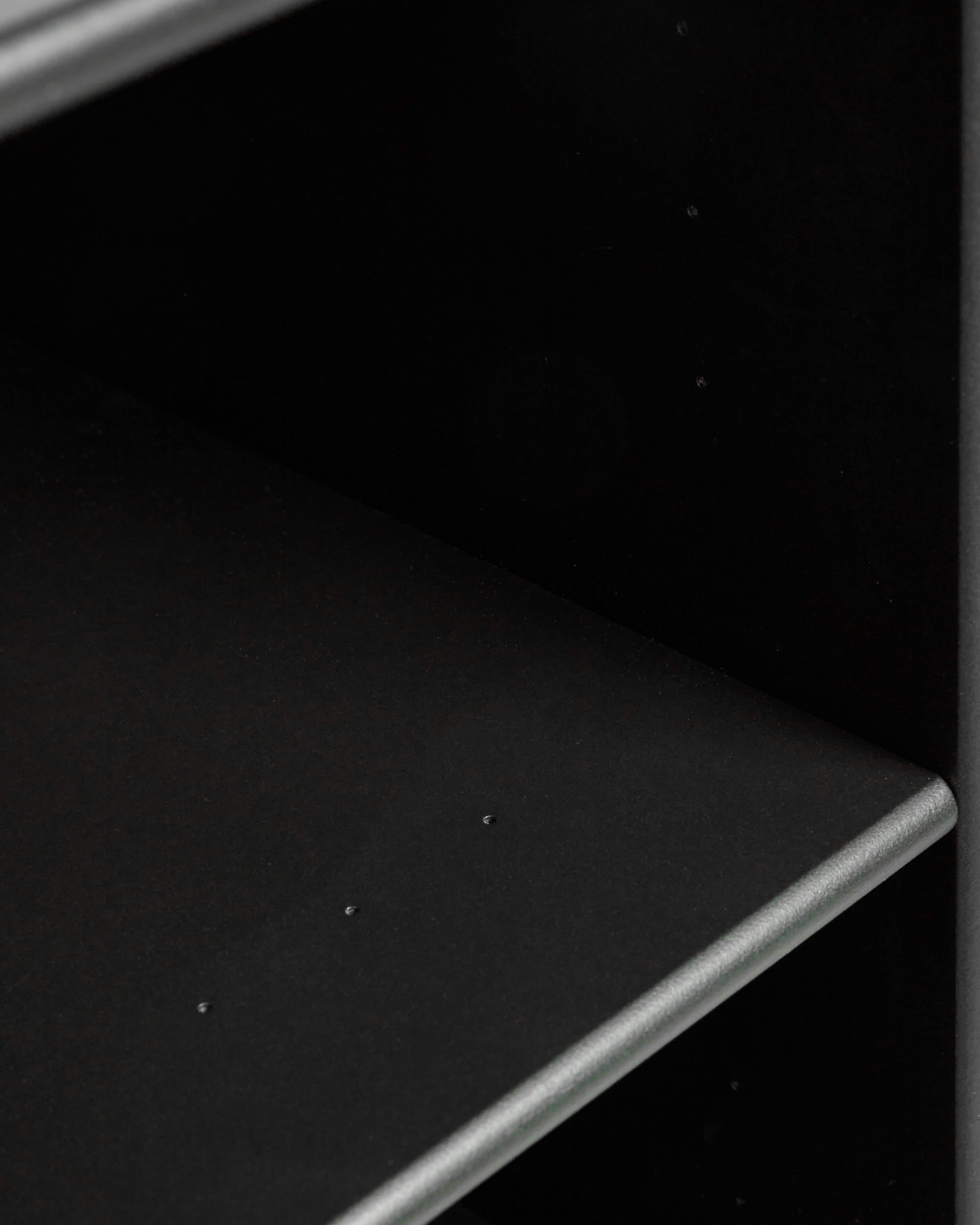 Close-up of an empty black WoodUpp Arka | Open Cabinet with a smooth finish and minor dents visible on the lower modular shelf.