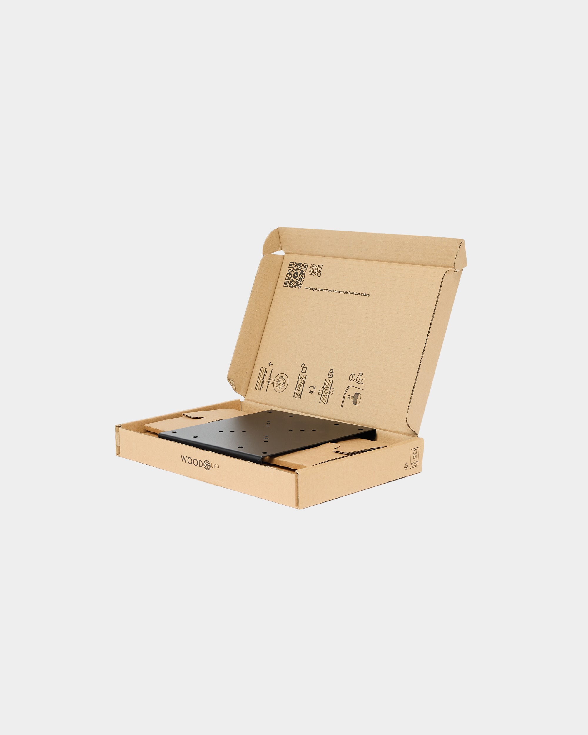 Black metal mounting plate in an open WoodUpp cardboard box on a plain white background