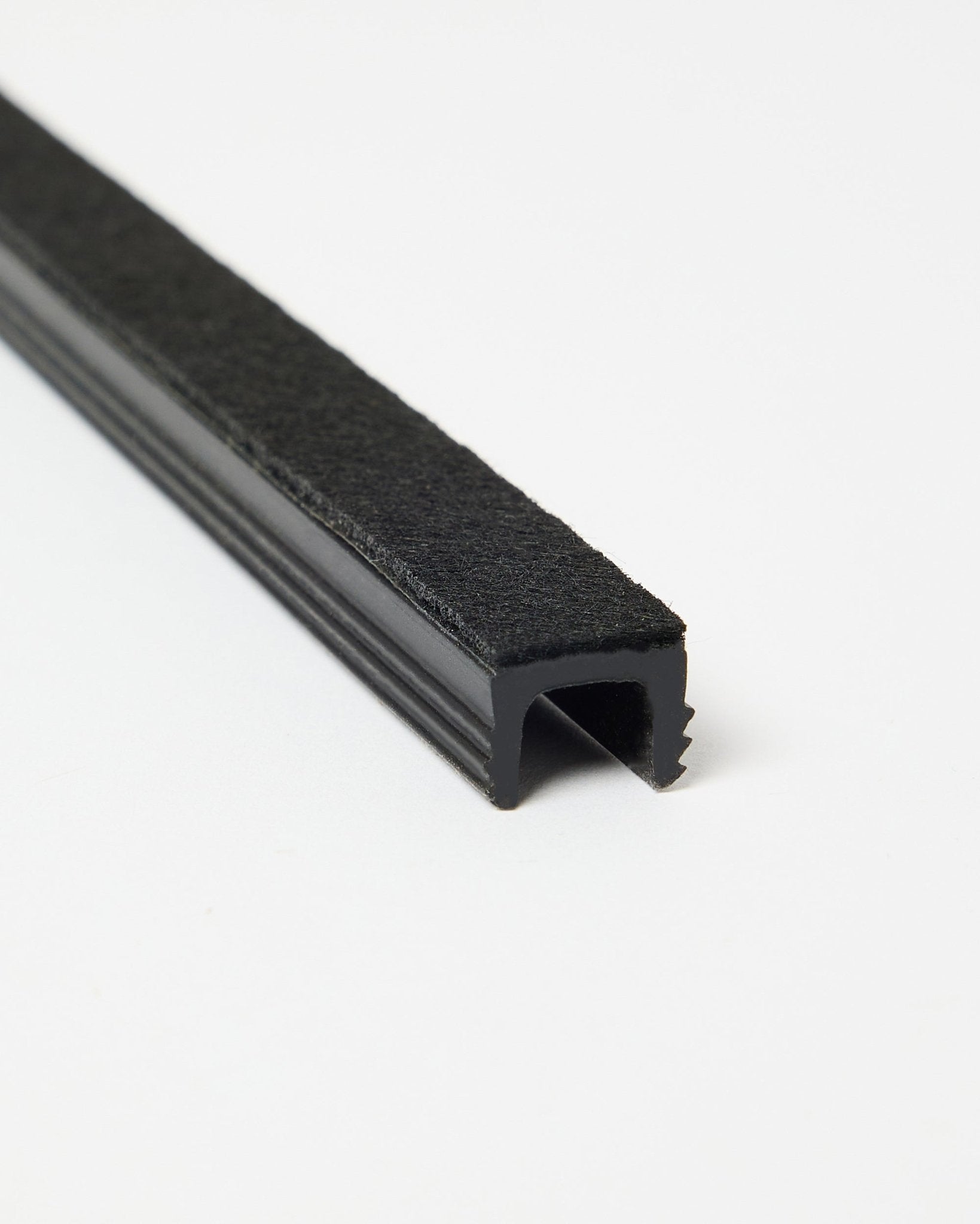 Black cable cover profile with felt top shown on a plain white background.