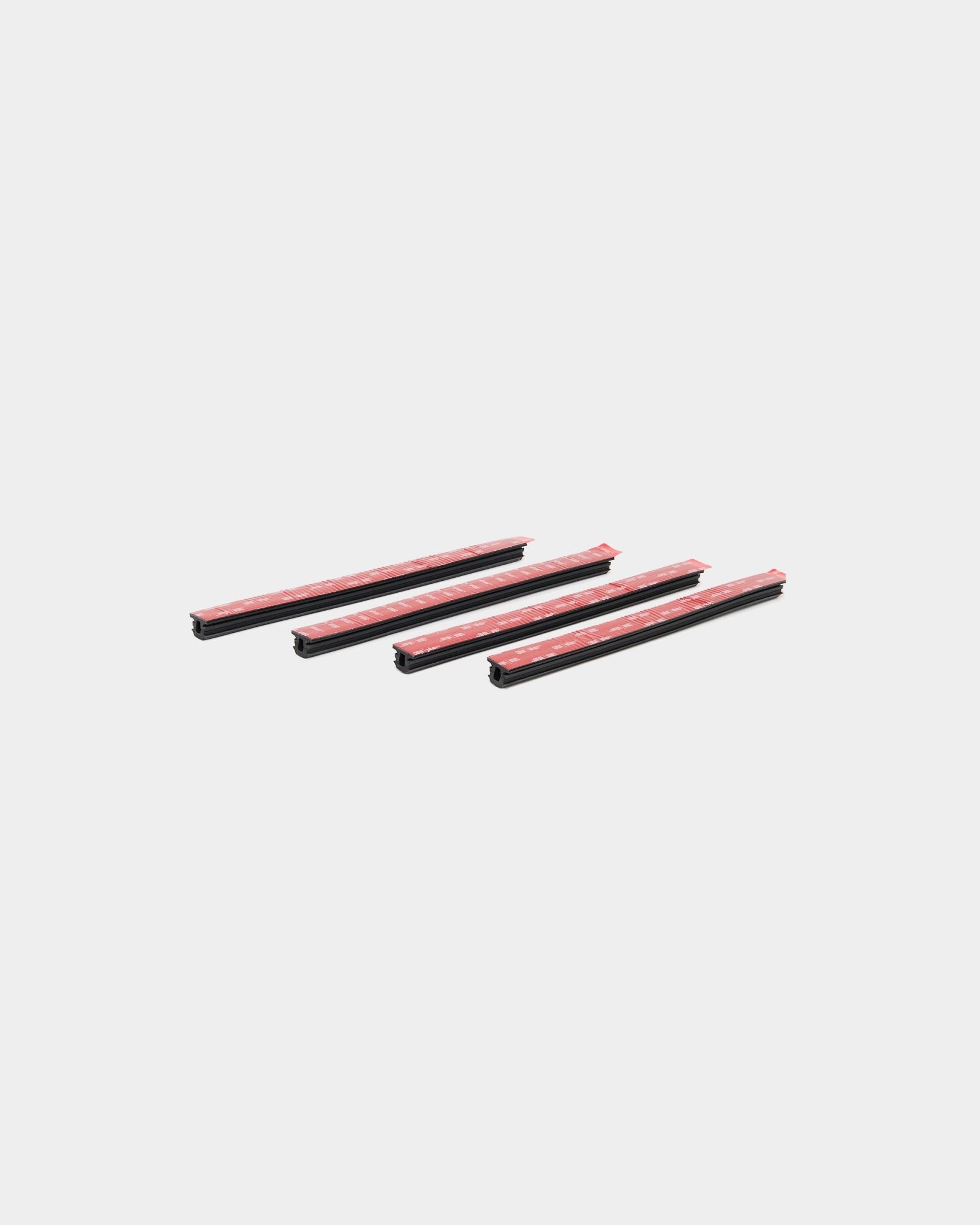 Four black Dupps Pop-on profile cover strips with red adhesive tape on a plain white background.
