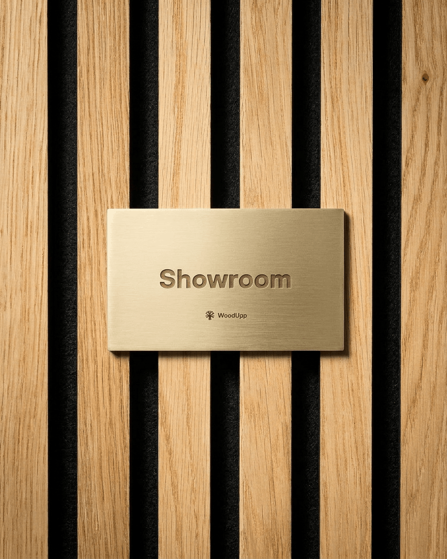 Brass showroom sign mounted on vertical light wood Akupanel acoustic panels with black gaps, using WoodUpp Dupps Pop-on Profile / Black accessories.