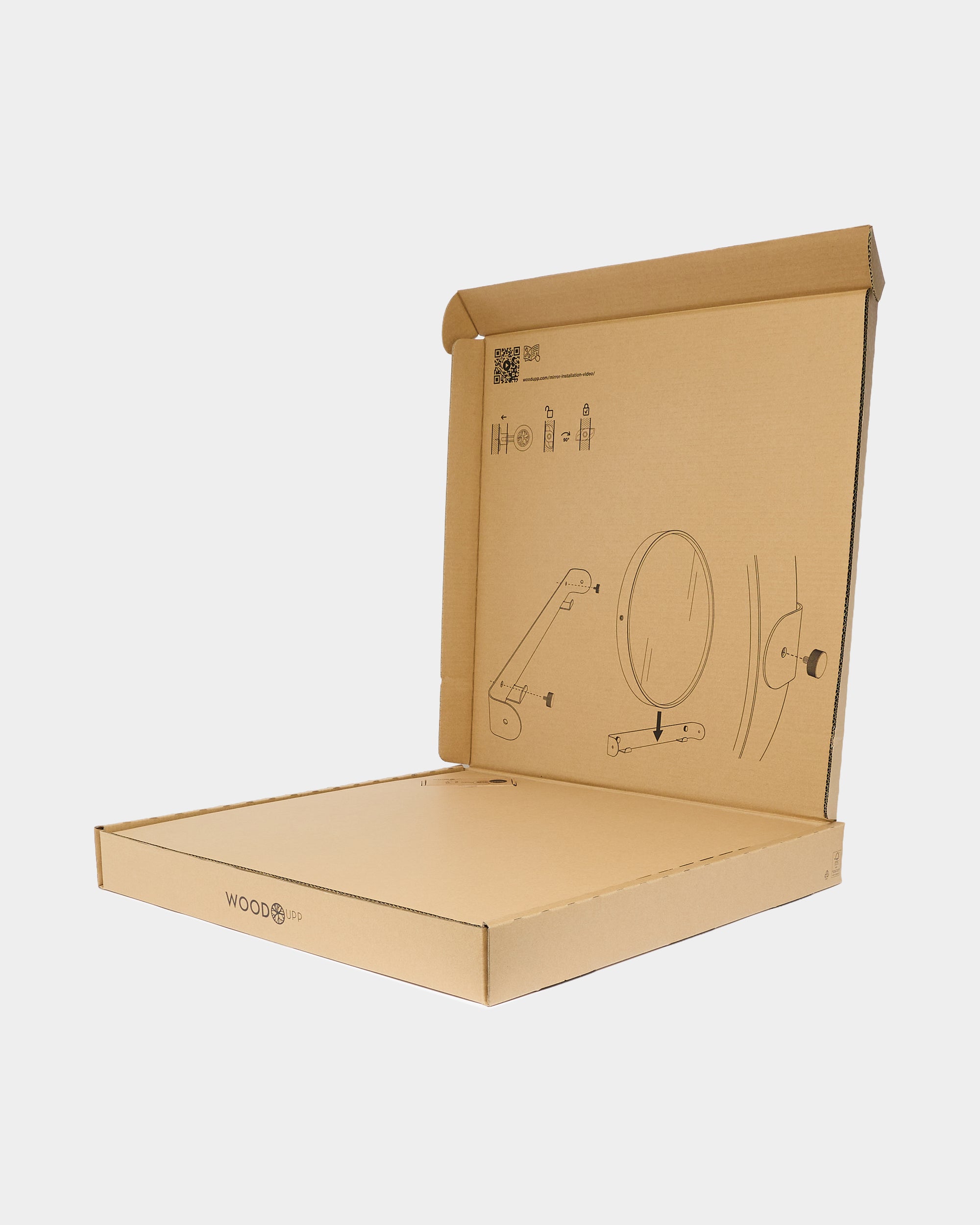 Open cardboard box with printed assembly diagrams of round mirror and bracket on plain grey background
