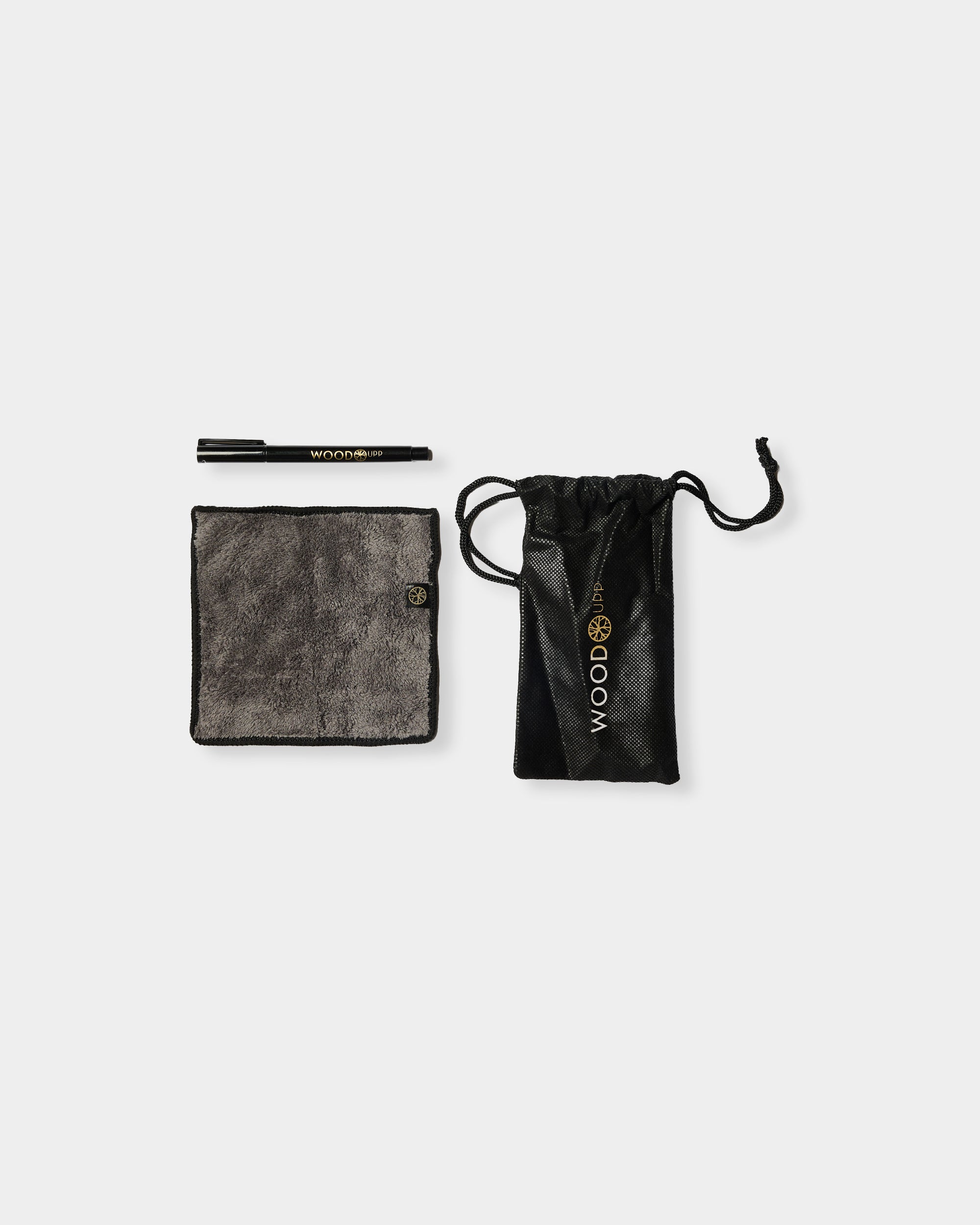 Black pen with gold WOODUPP logo, gray microfiber cloth and black drawstring pouch on a plain white background.