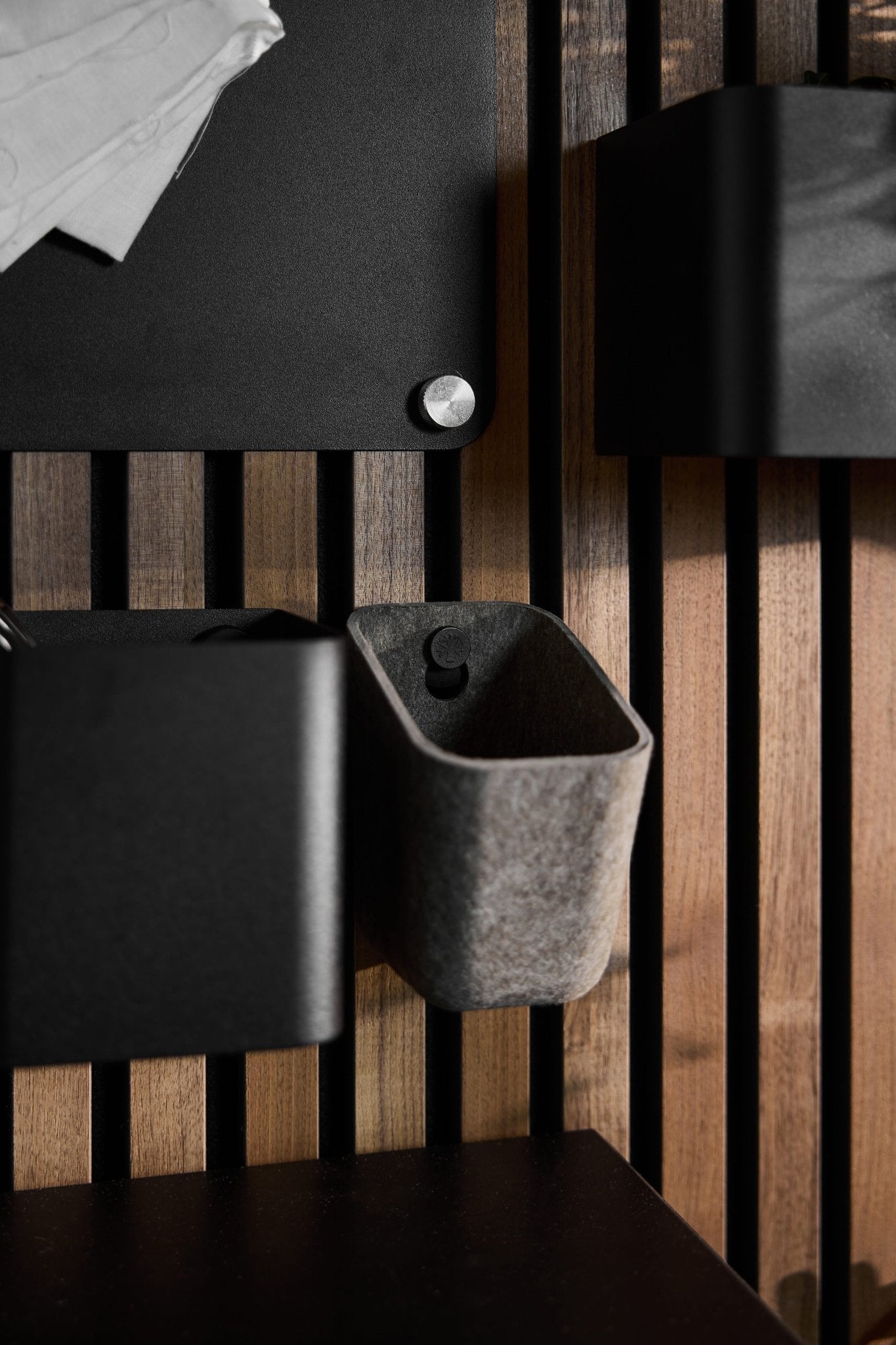 Close-up of Dupps | Light storage bins by WoodUpp, mounted on a Nordic Akupanel acoustic wood panel; white paper visible in the upper left corner.
