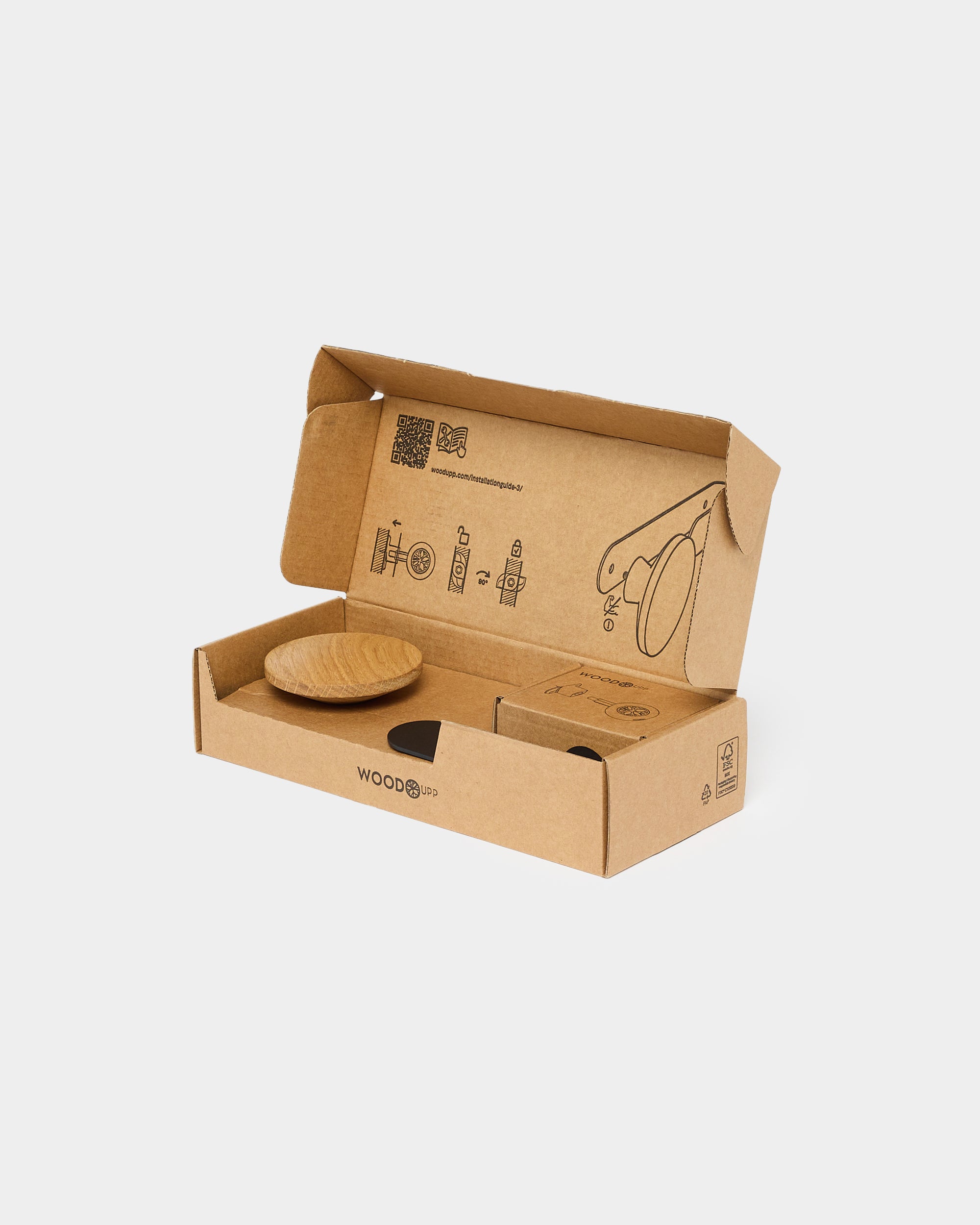 Round wooden wall hanger in open cardboard box with printed assembly instructions on white background