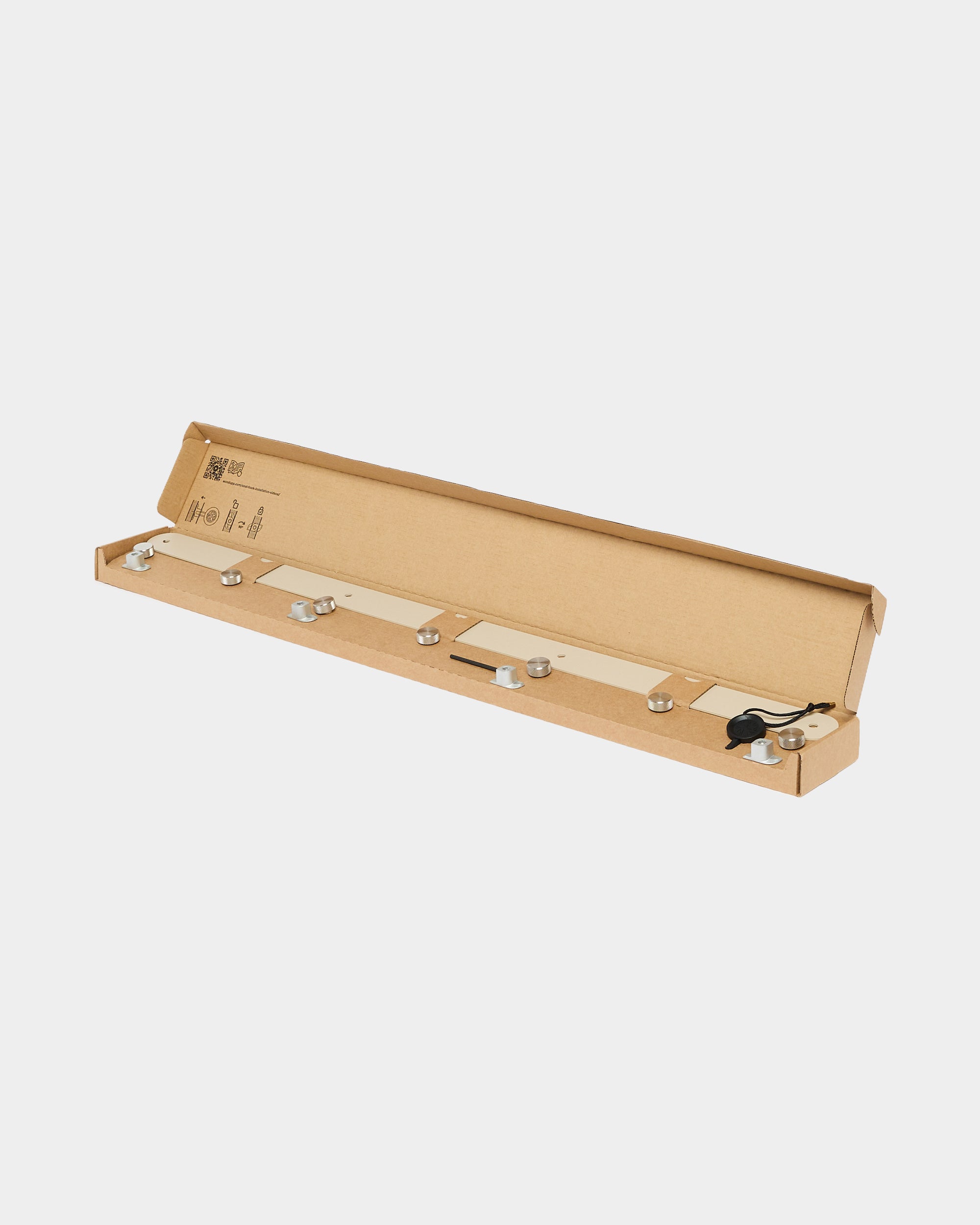 Mounting hardware kit with metal standoffs and black cord in open cardboard box on white background