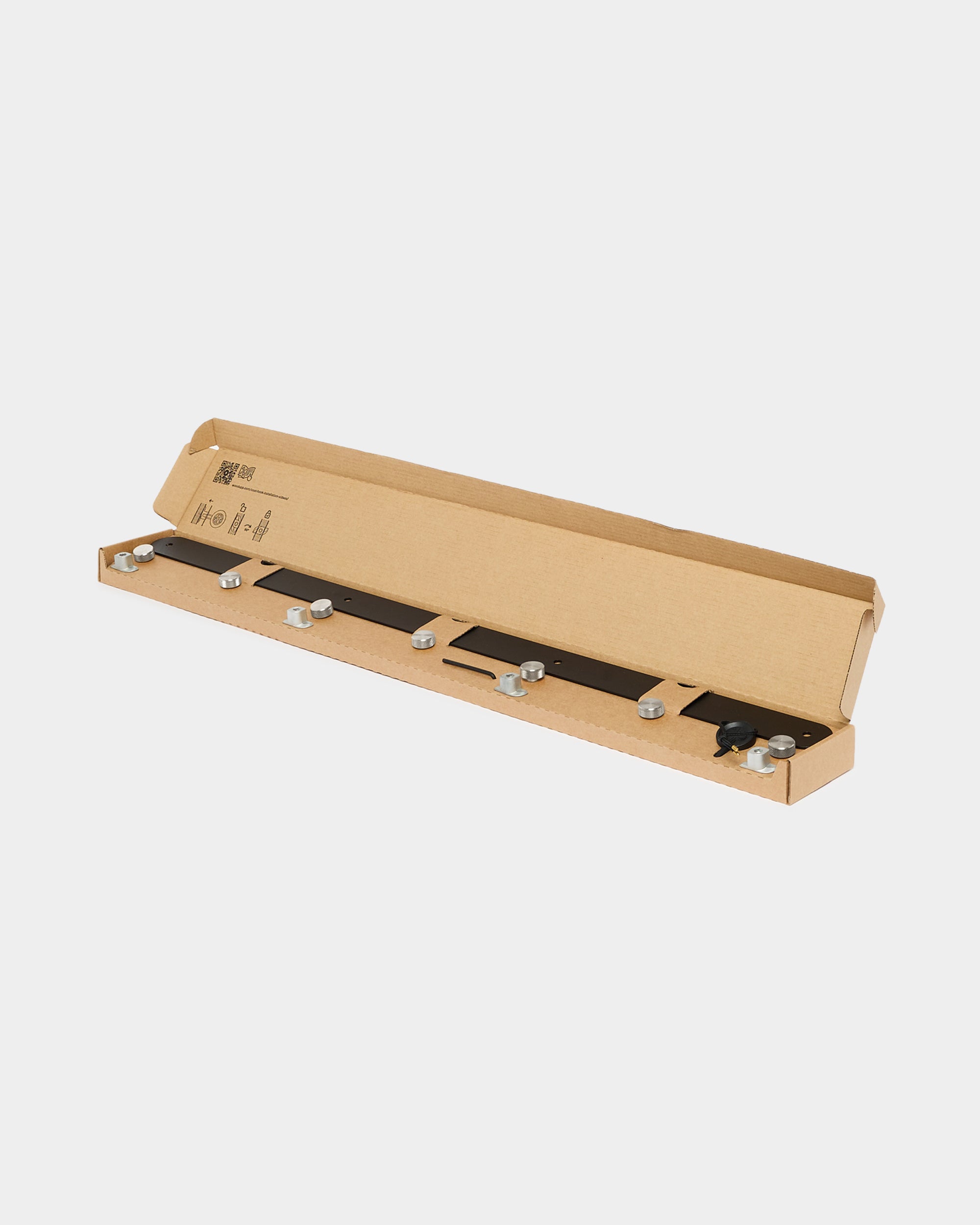 Black Norr coat hook rack and metal mounting hardware in a cardboard box on a plain white background
