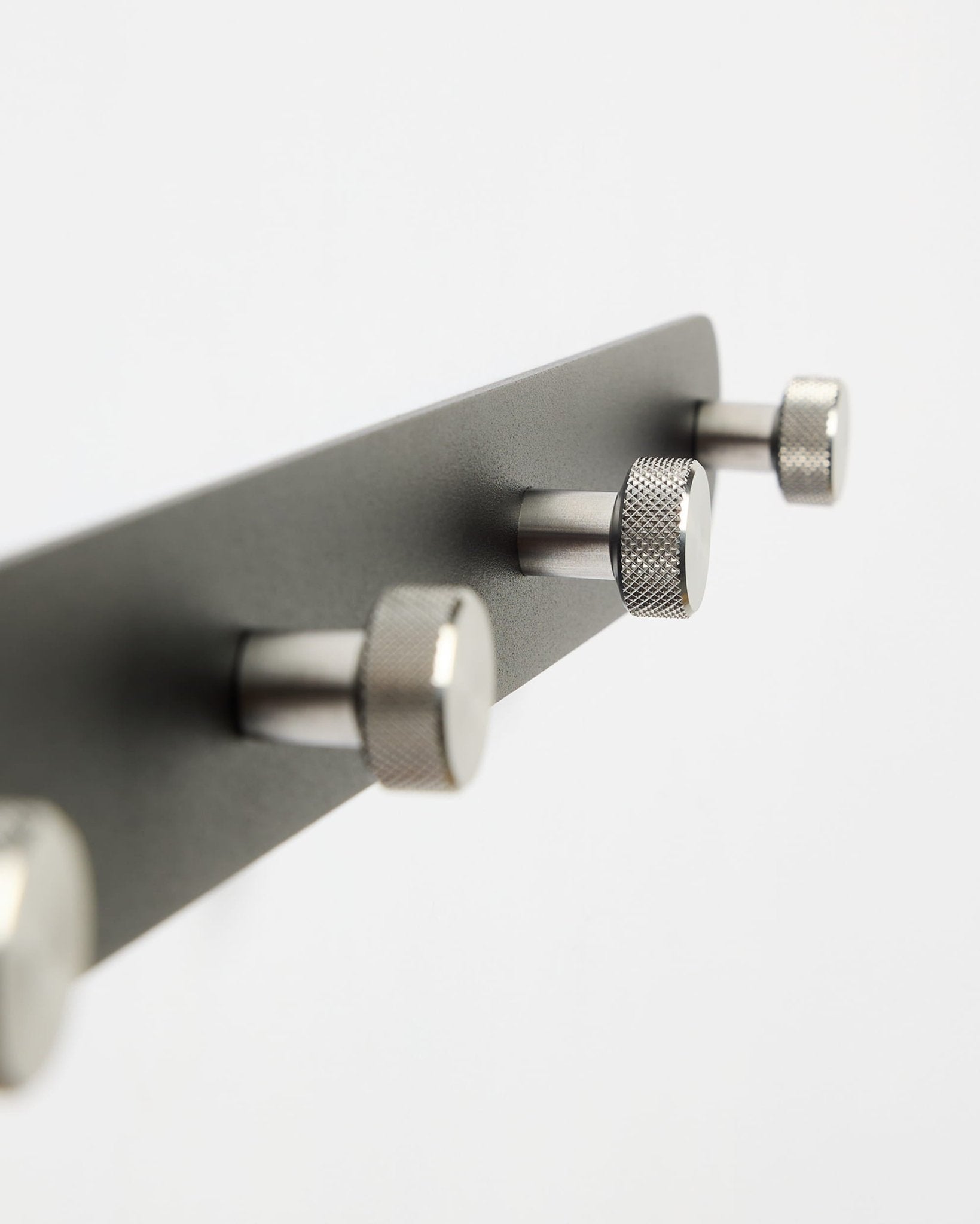 Norr coat hook rack in black with stainless steel knobs on plain white background