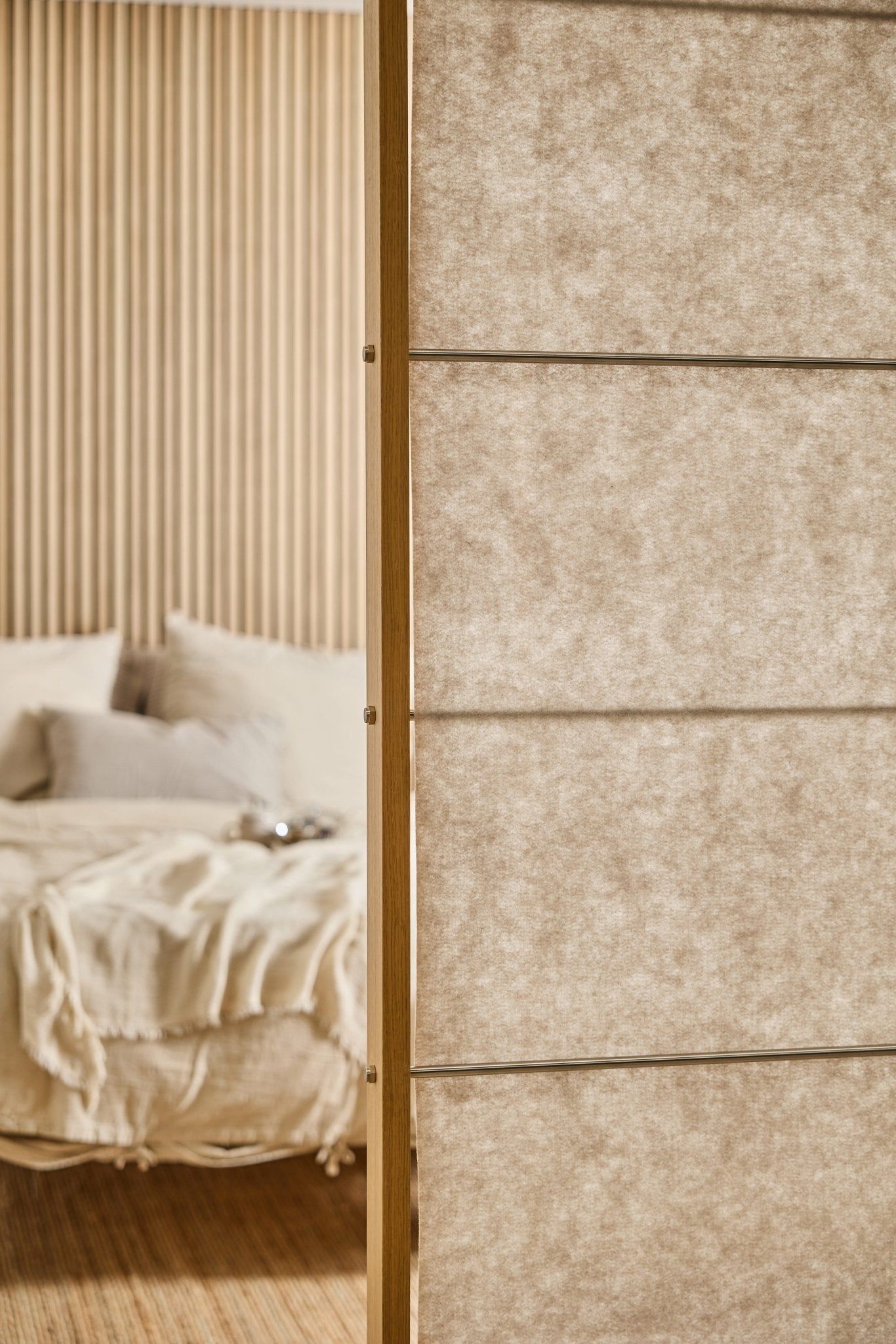 Bedroom with a beige bed, soft blanket, and a Light Beige Vigg Felt Sheet (58x241cm) EMBRACE room divider by WoodUpp in the foreground.