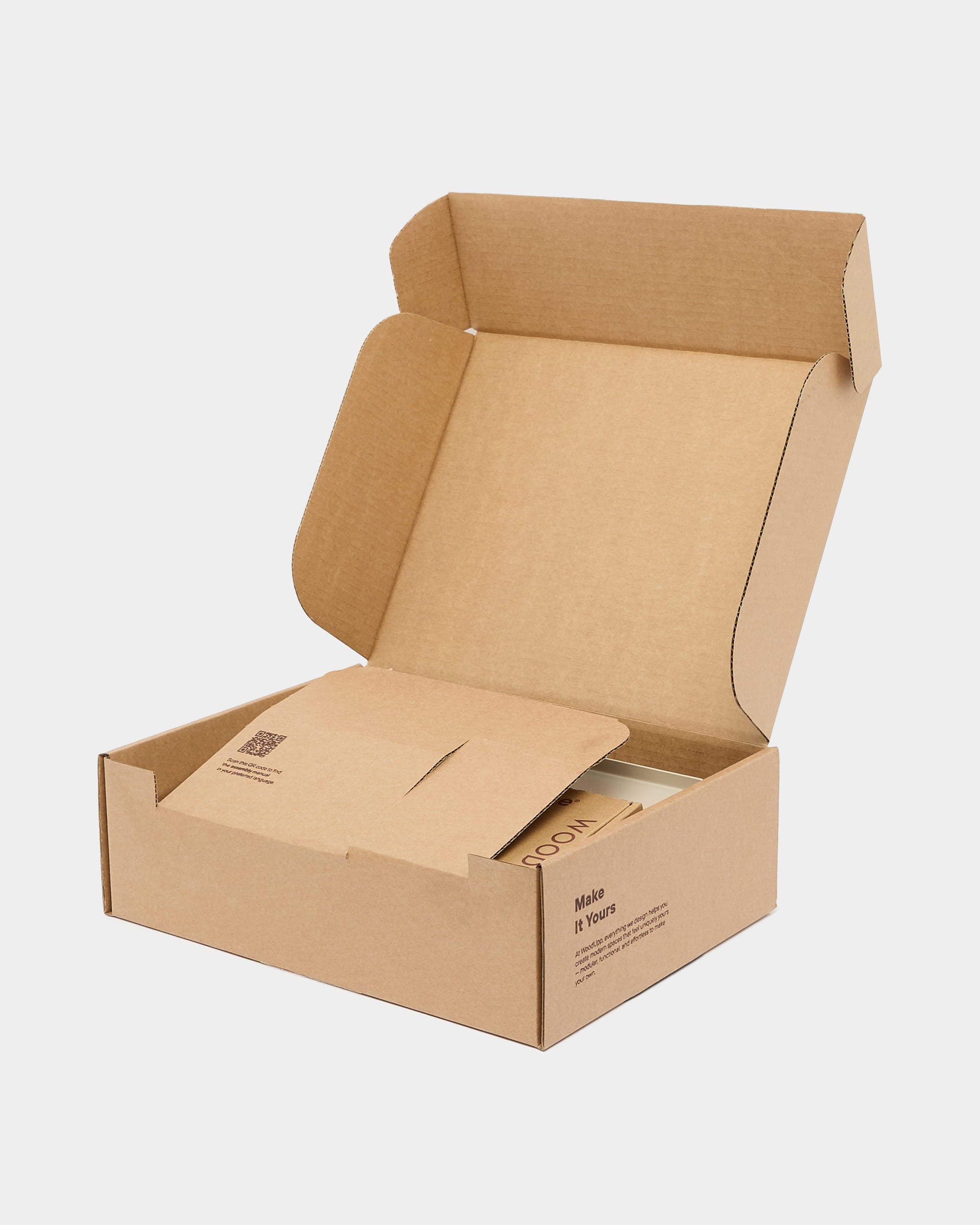 An open cardboard box with a flap, showing sustainable packaging material and a partially visible WoodUpp card, ready for an acoustic panel shipment.
