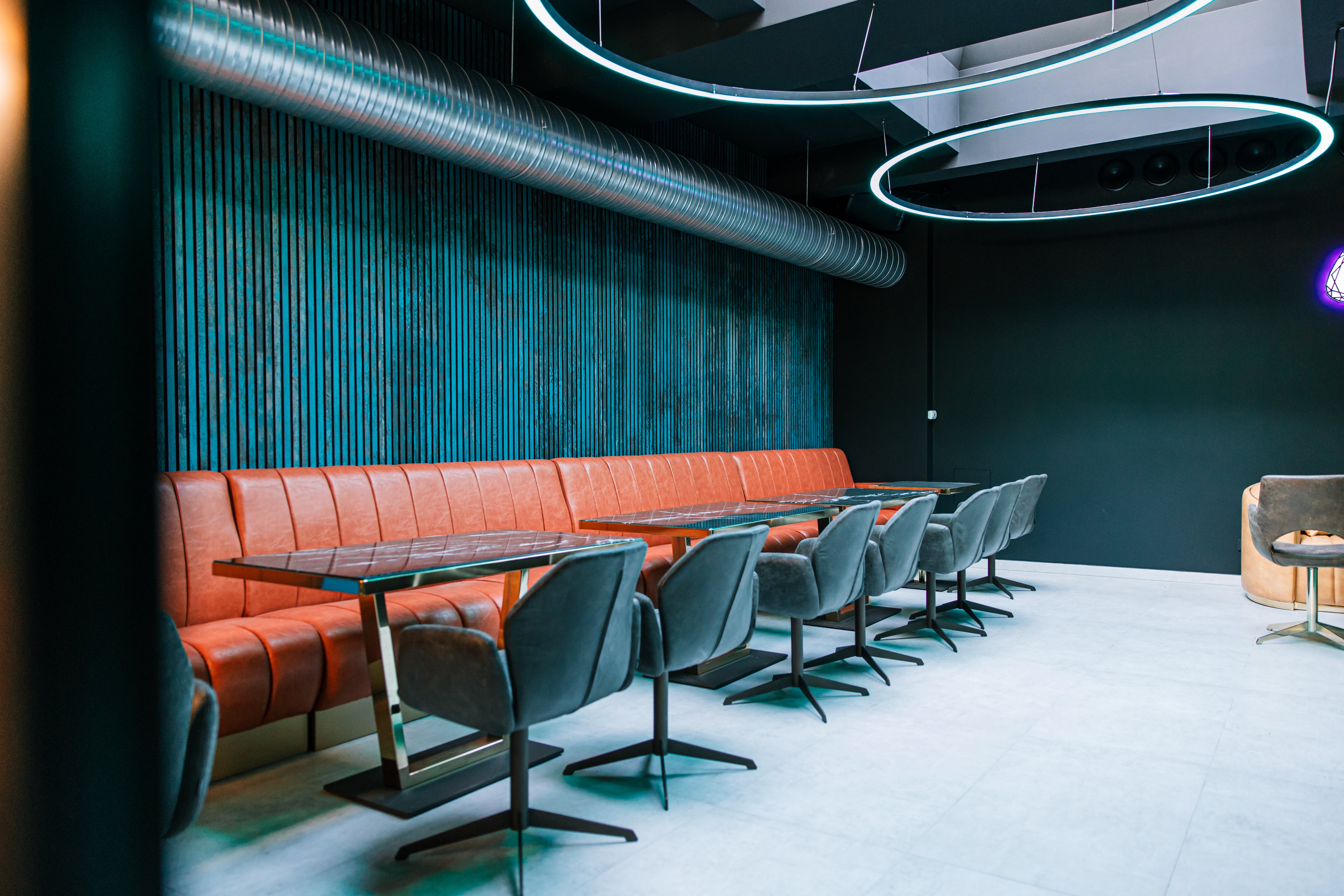 Teal Akupanel acoustic slat wall panels behind leather banquette seating in a restaurant interior.