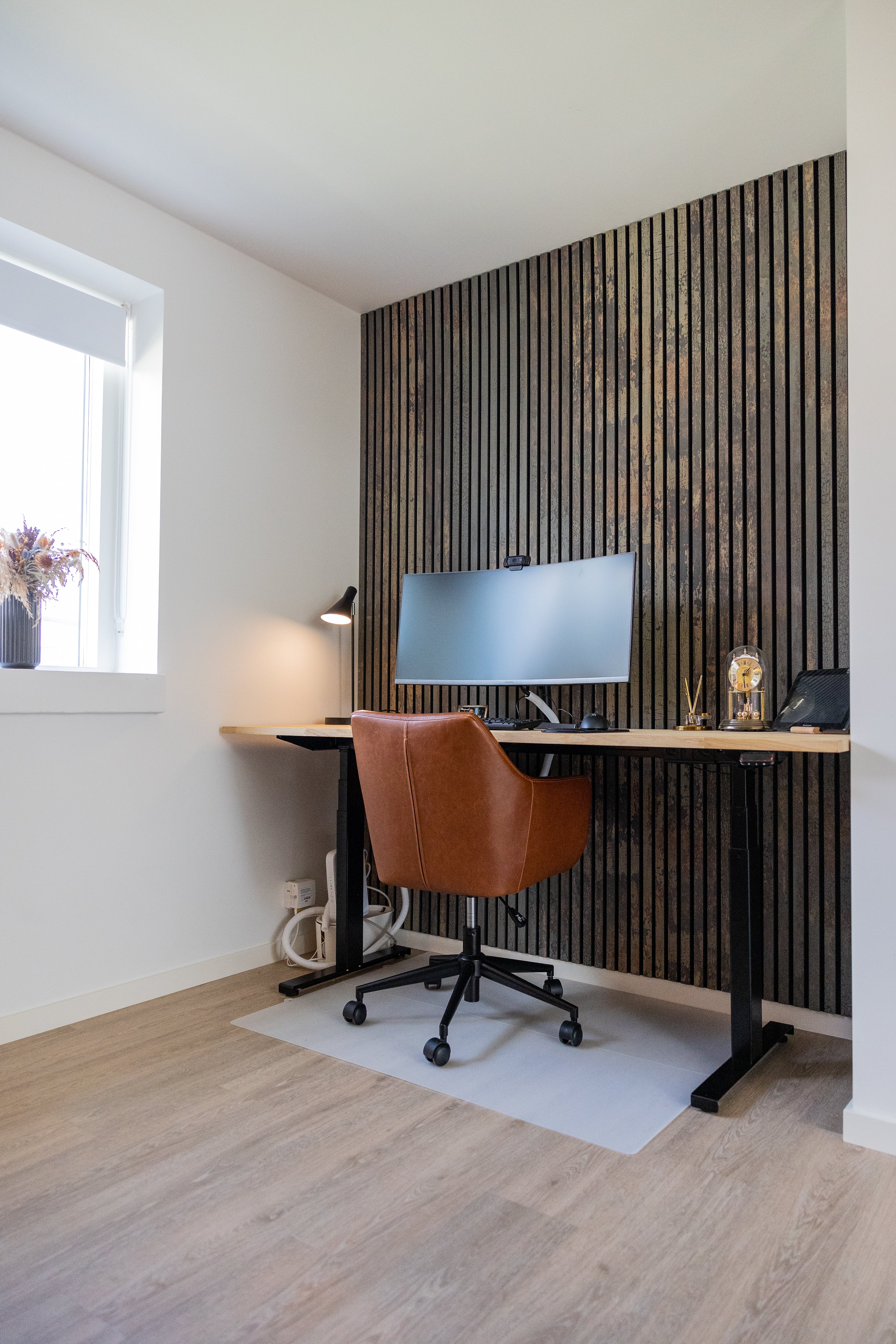 Akupanel dark vertical slat acoustic wall panels behind a desk in a home office.