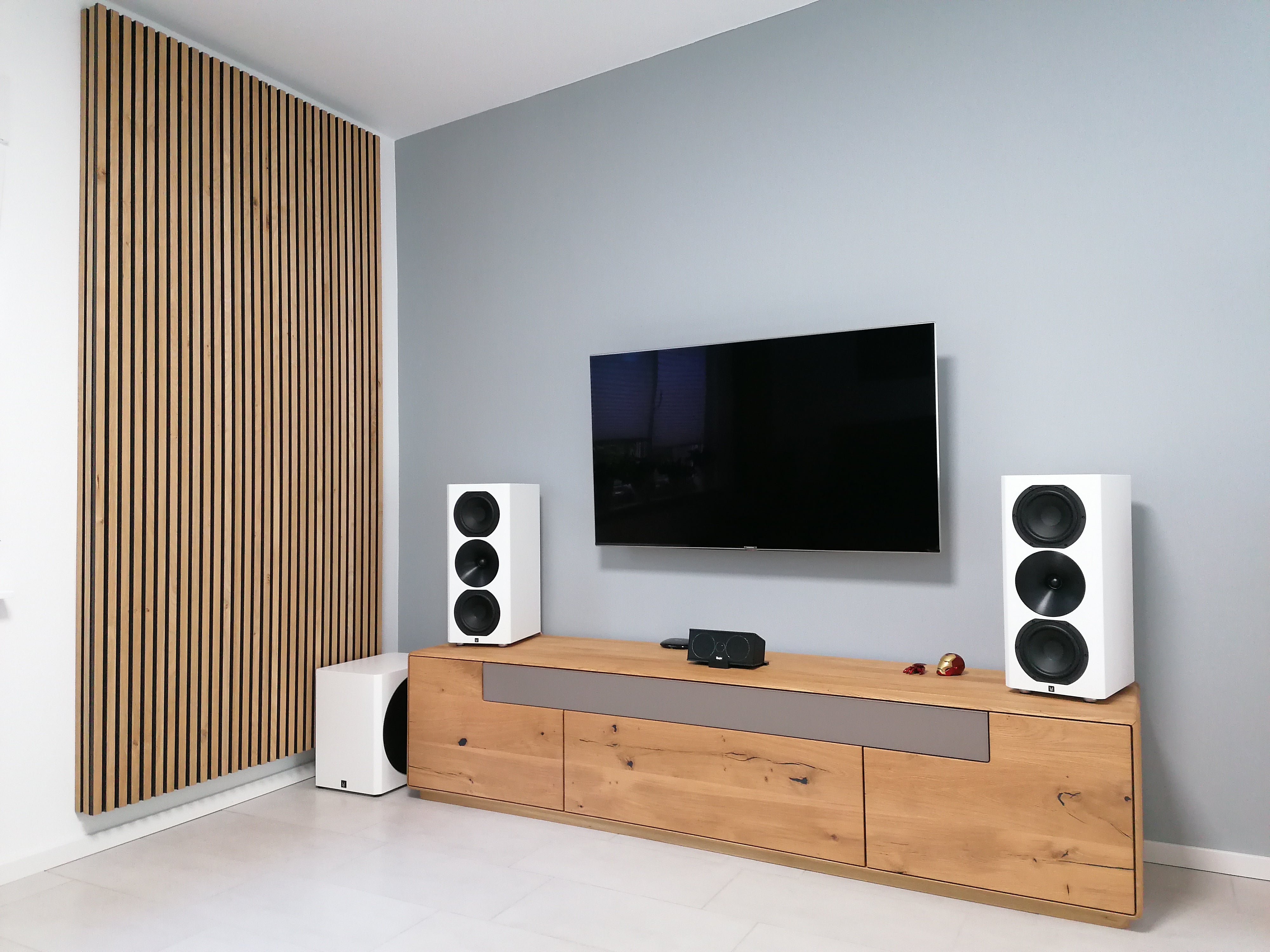 Akupanel acoustic slat wall panel with wood slats on black backing, next to TV