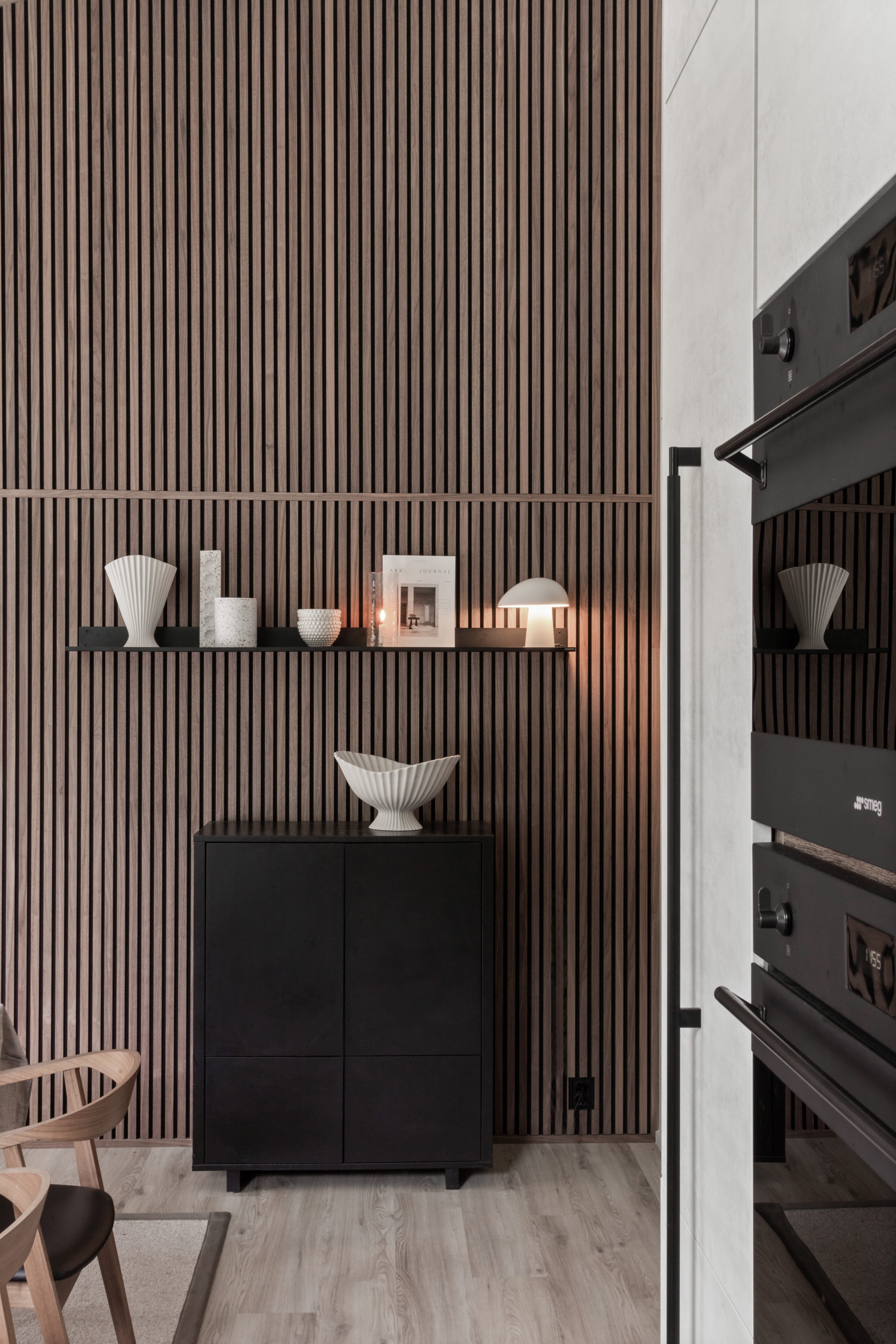 Akupanel wood slat acoustic wall panels with dark finish on interior wall beside oven