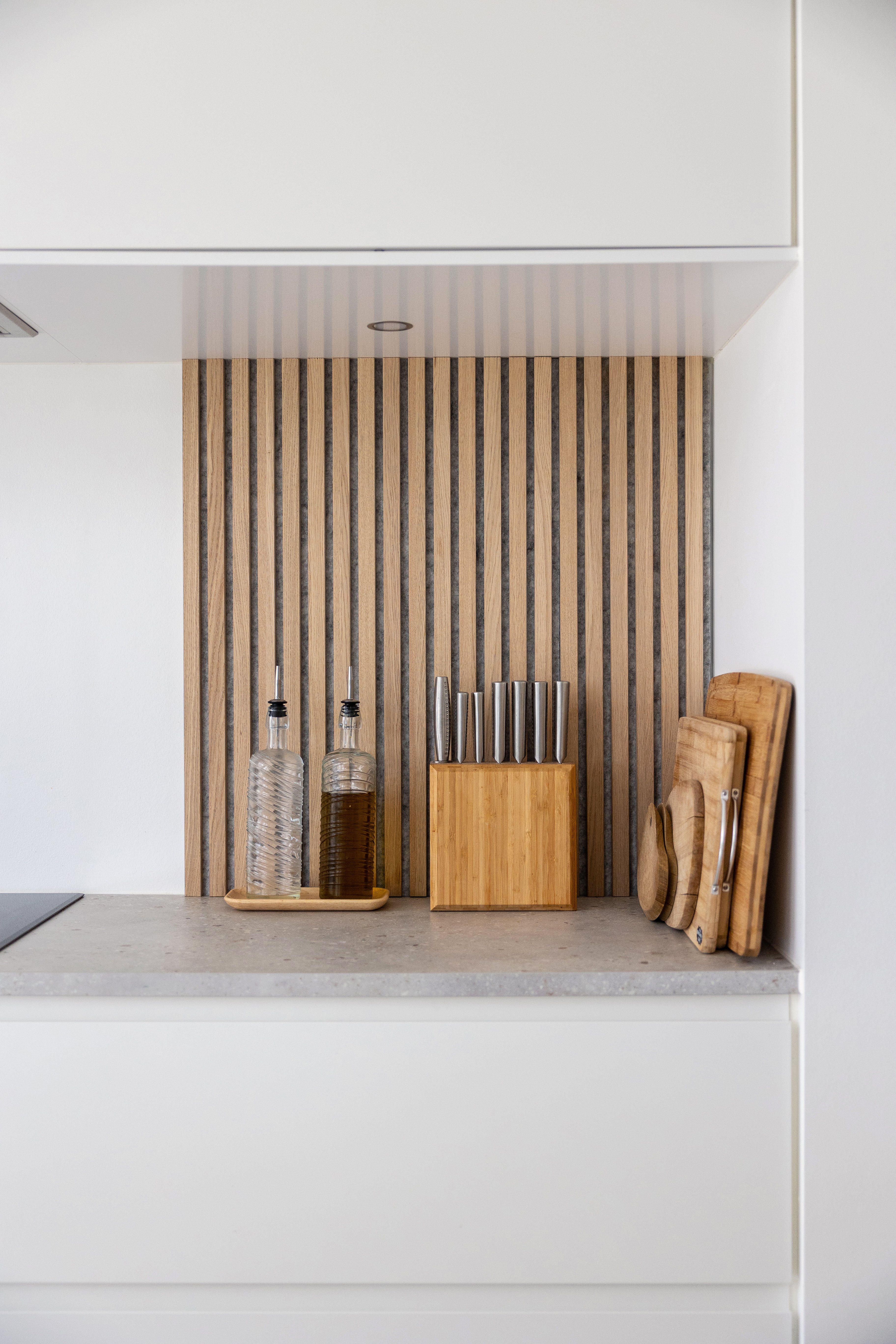 Akupanel wood slat acoustic wall panel mounted in a white kitchen alcove behind countertop items.