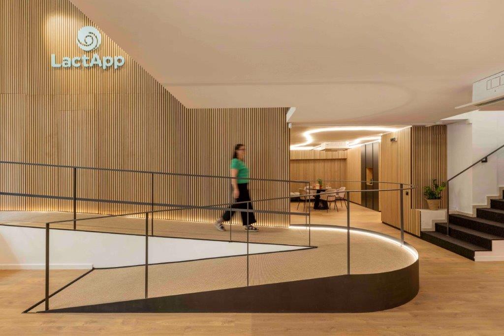 Akupanel acoustic slat wall panels in light wood on reception interior with curved ramp and seating