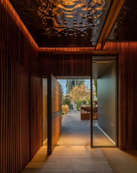 Akupanel acoustic slat wall panels lining a lit interior entryway opening to an outdoor courtyard.