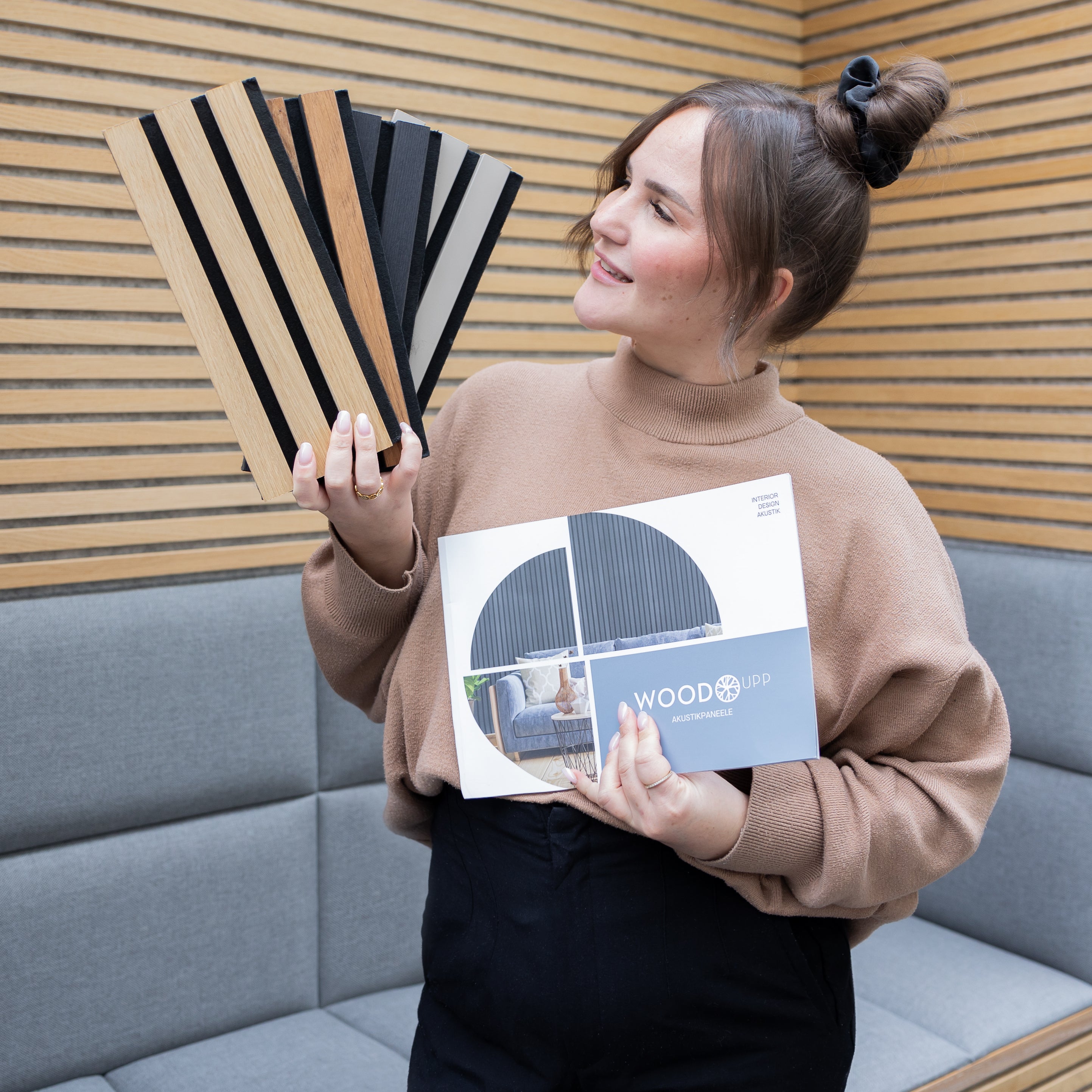 Woman holding Akupanel slat samples and brochure against wood acoustic slat wall panels