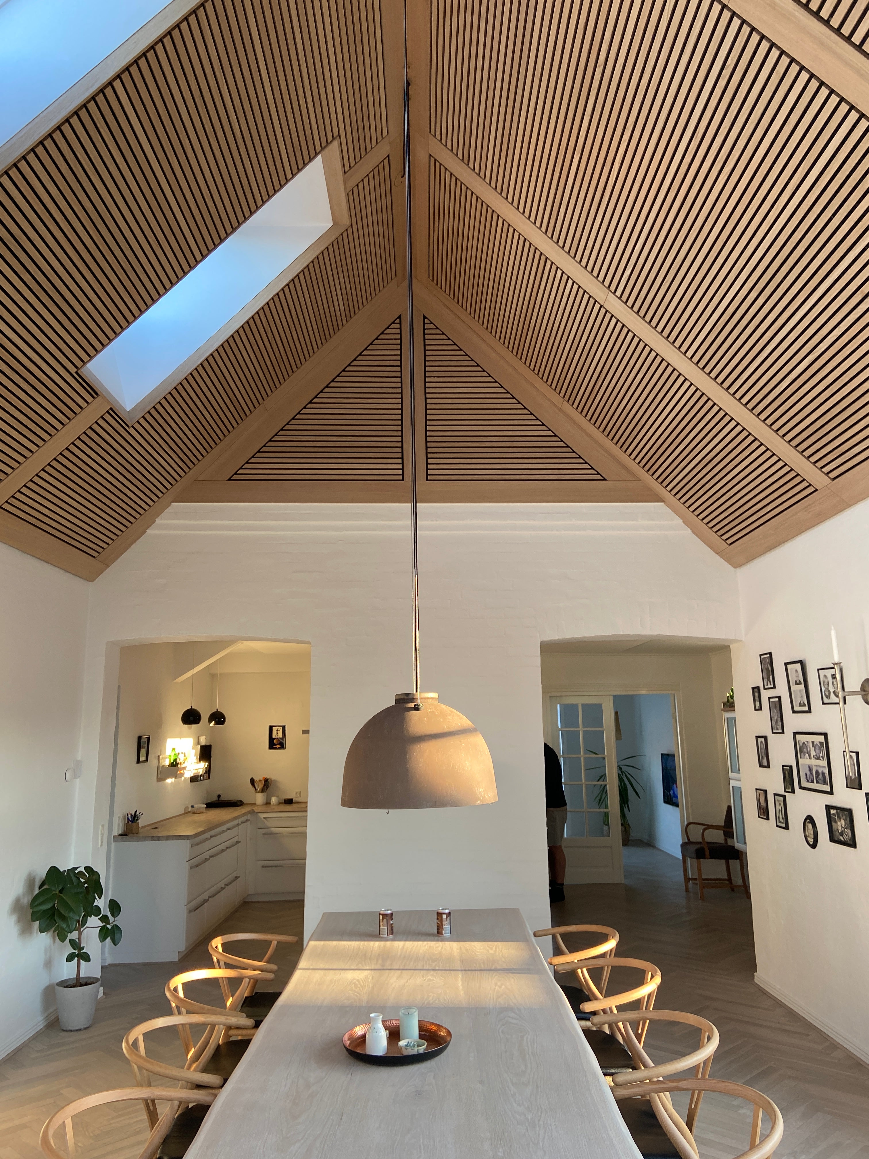 Oak Akupanel acoustic slat panels on a vaulted ceiling with skylight above a dining room.