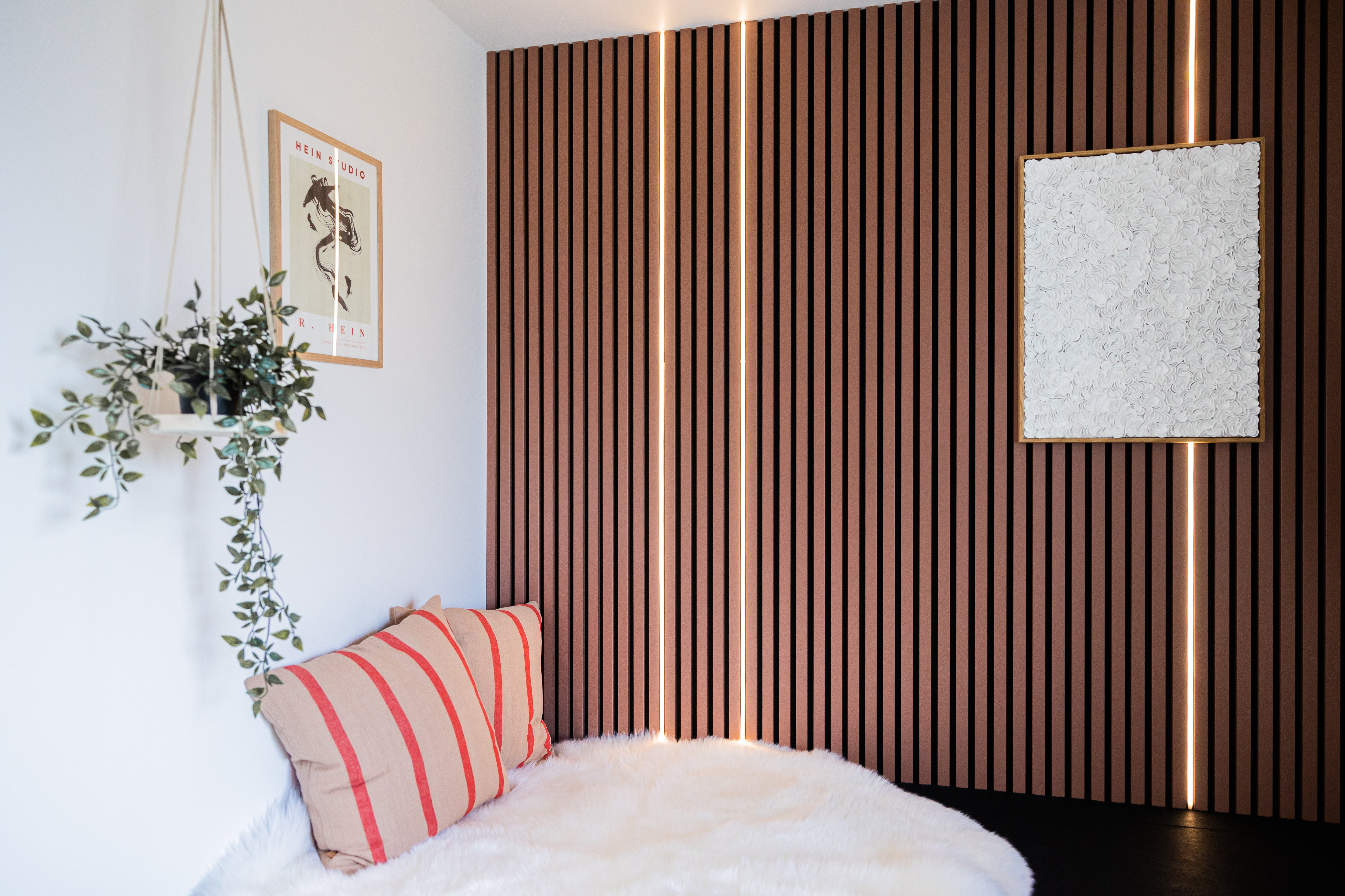 Akupanel acoustic slat wall panels, brown wood slats with vertical LED strips beside bed