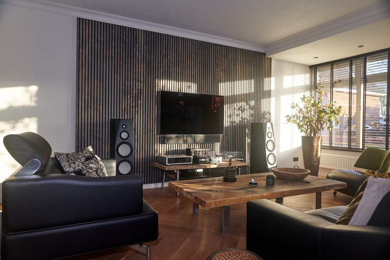 Akupanel acoustic slat wall panels, dark finish, behind TV and speakers in a sunlit living room.