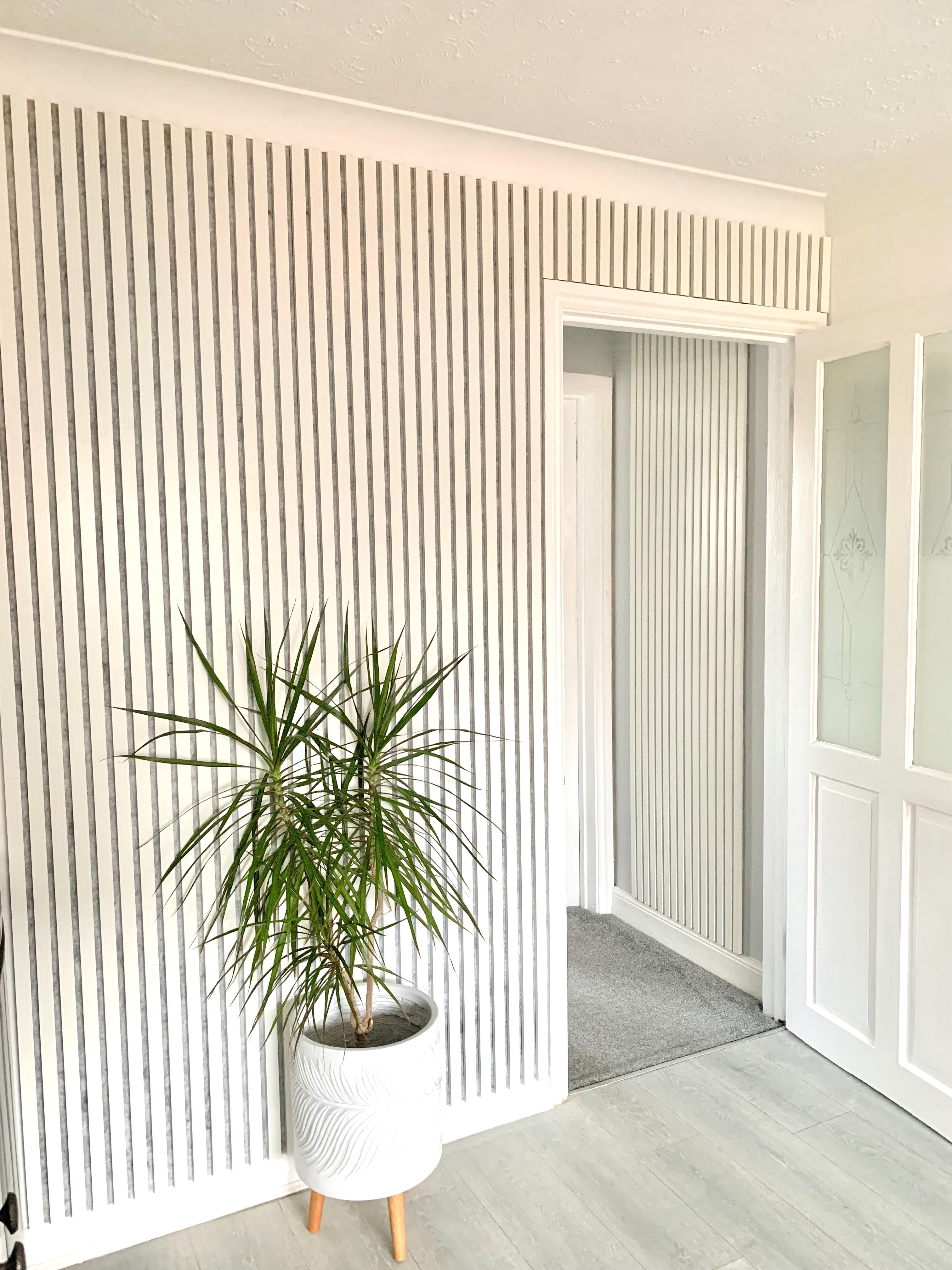White Akupanel acoustic slat wall panels on interior wall - potted plant and doorway