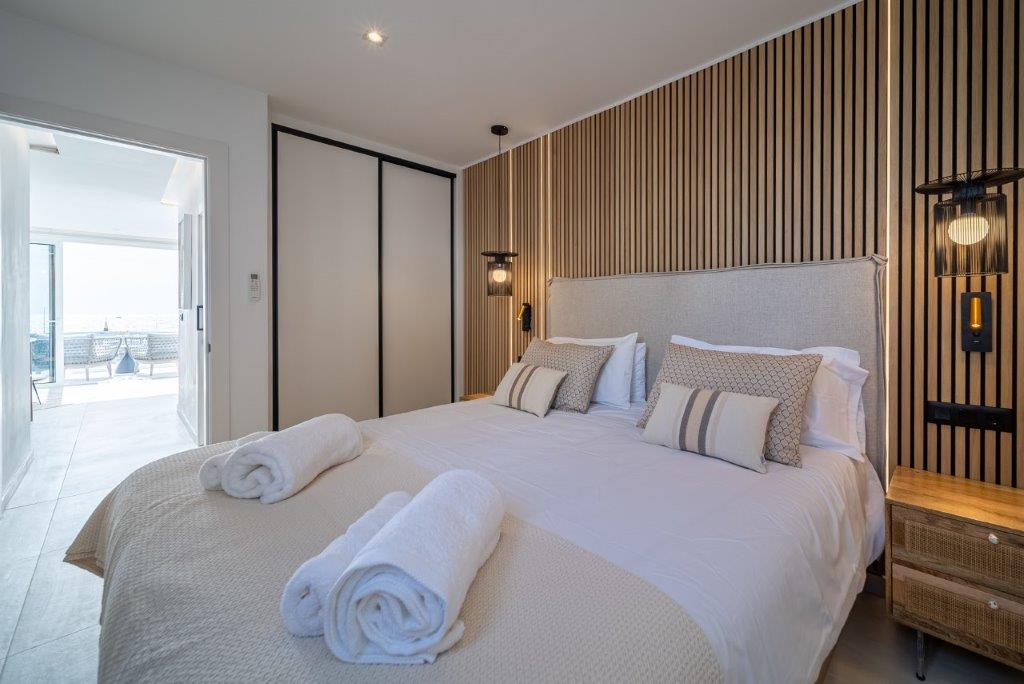 Akupanel wood slat acoustic panels behind a bed in a bright bedroom with balcony